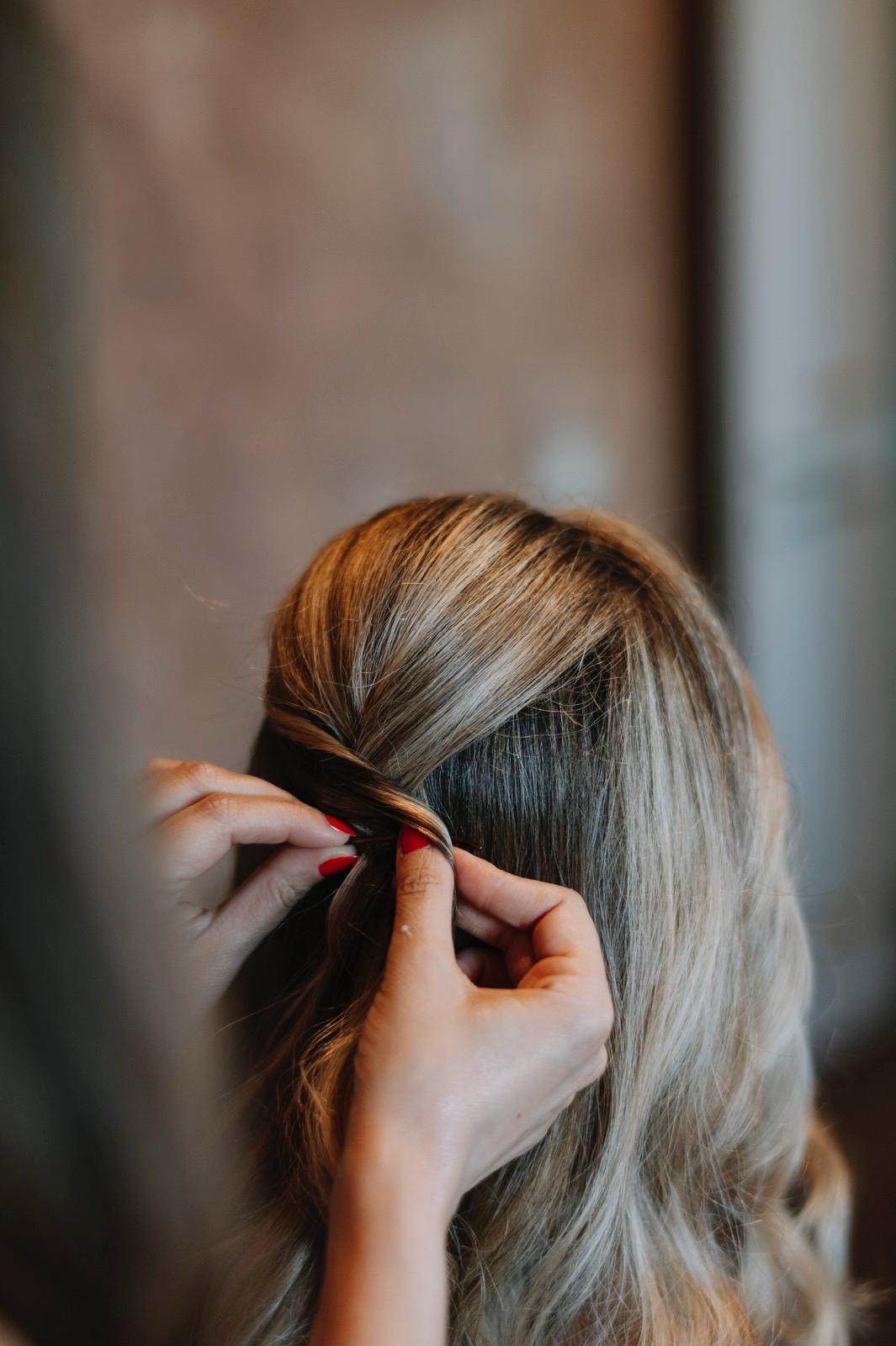 Mani di Francesca mentre lavora una sezione di capelli biondi